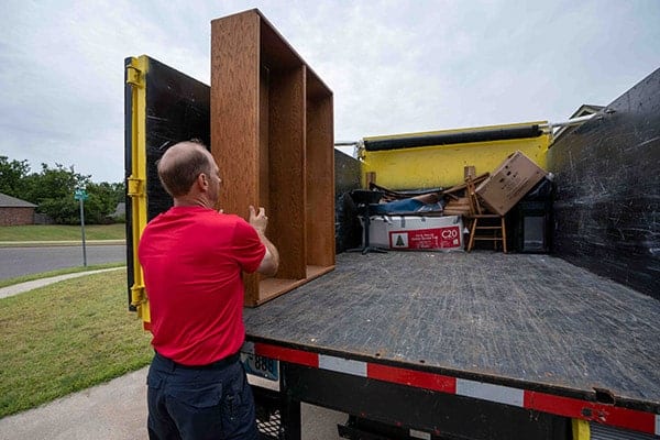 Junk removal professional loading shelves into the back of a junk removal truck