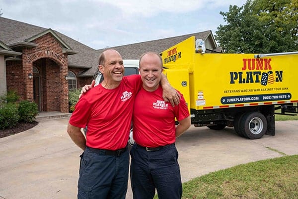 Junk removal professionals standing in front of their truck