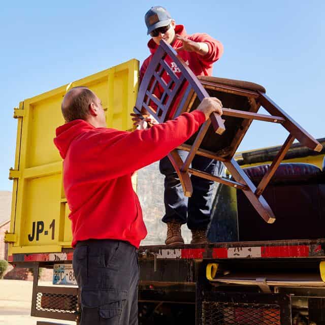 junk removal technicians loading furniture from a storage unit cleanout in edmond